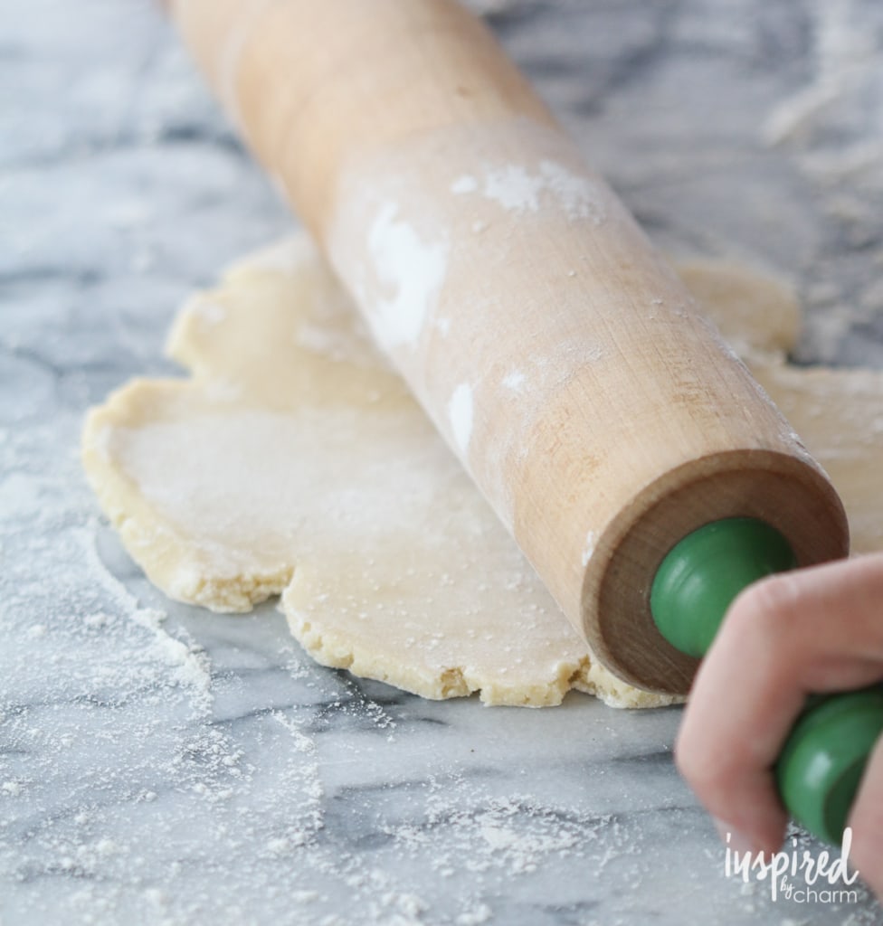 rolling out dough dusted with flour on a counter