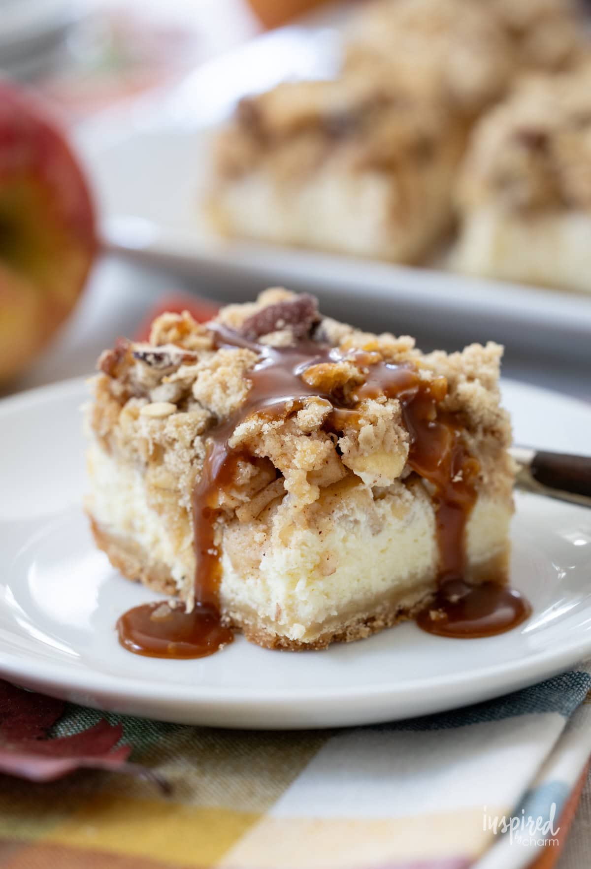 single Salted Caramel Apple Cheesecake Bar on a plate drizzled with caramel.