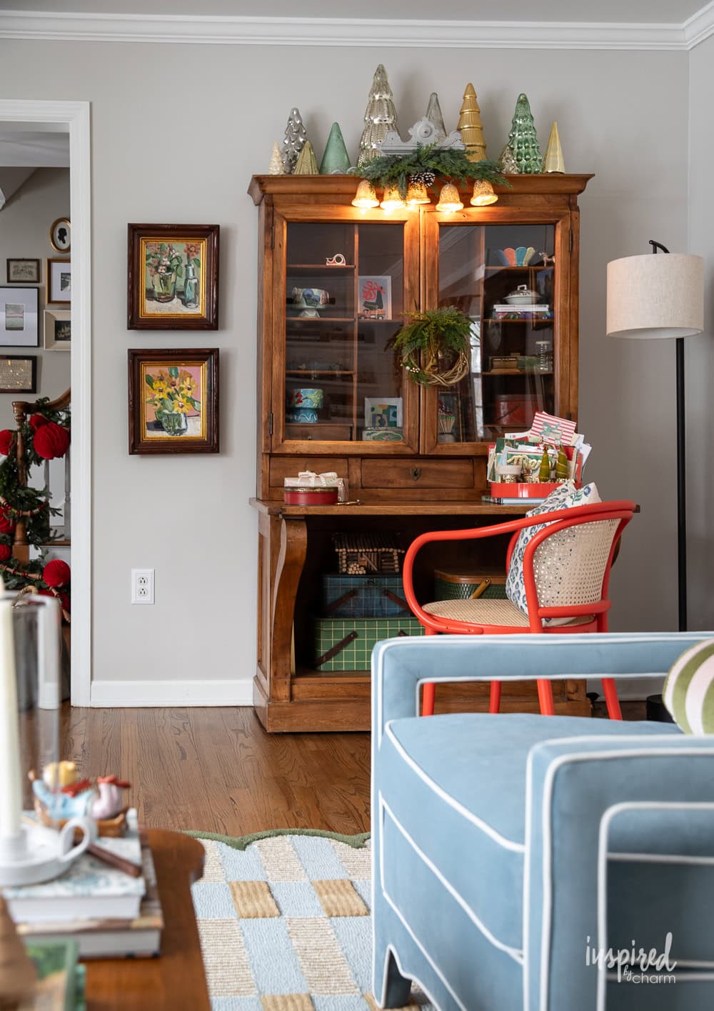 secretary desk decorated for Christmas with artwork and red chair.