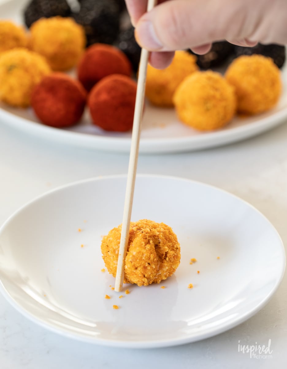 hand with skewer adding lines to cheese ball.