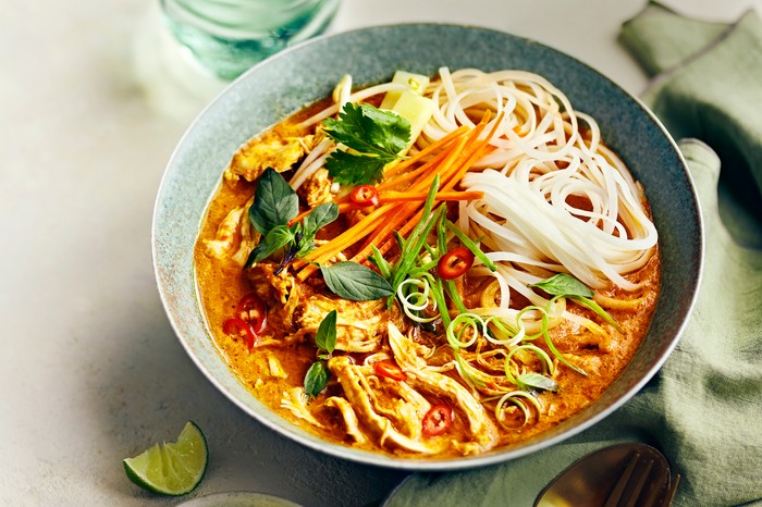 Bowl of Coconut Chicken Soup with Noodles and Fresh Lime