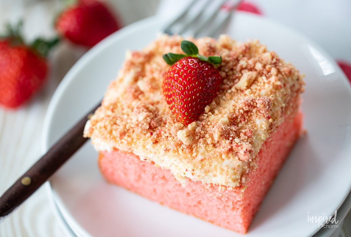 slice of strawberry crunch cake on a plate with a fork.