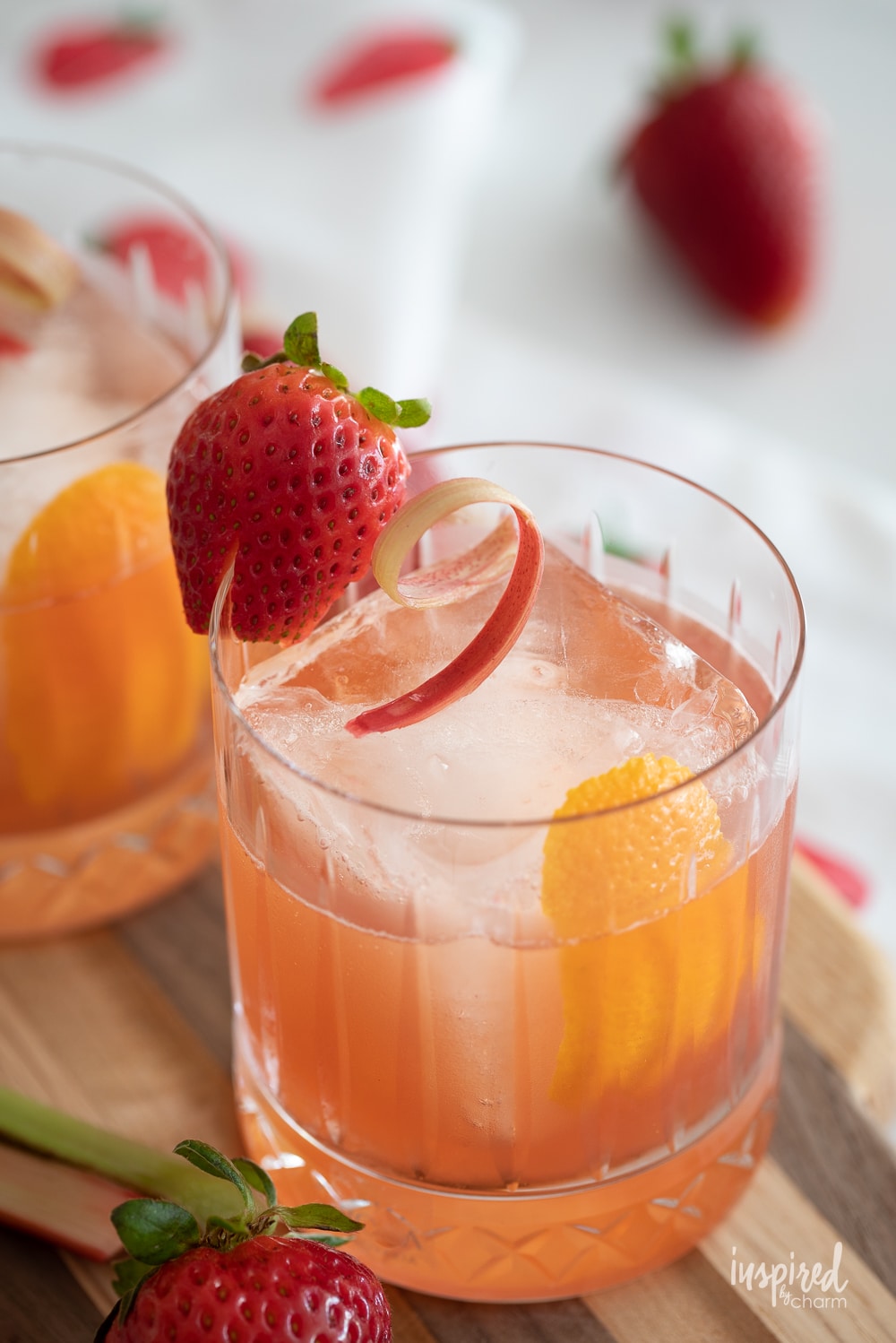 strawberry rhubarb old fashioned made and served in a rocks glass with strawberry.