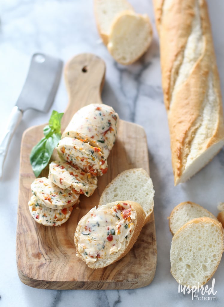 Sliced baguette next to butter mixed with sun dried tomatoes.