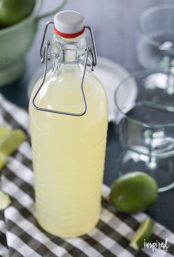 bottle of the best homemade margarita mix next to a lime.