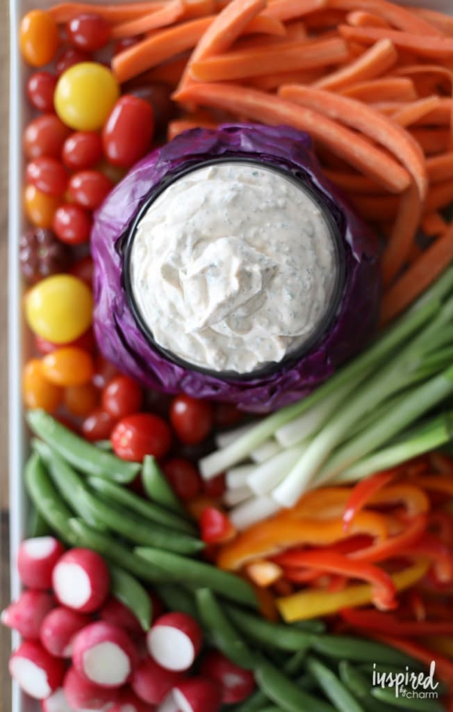 a bowl of dip surrounded by cut up veggies