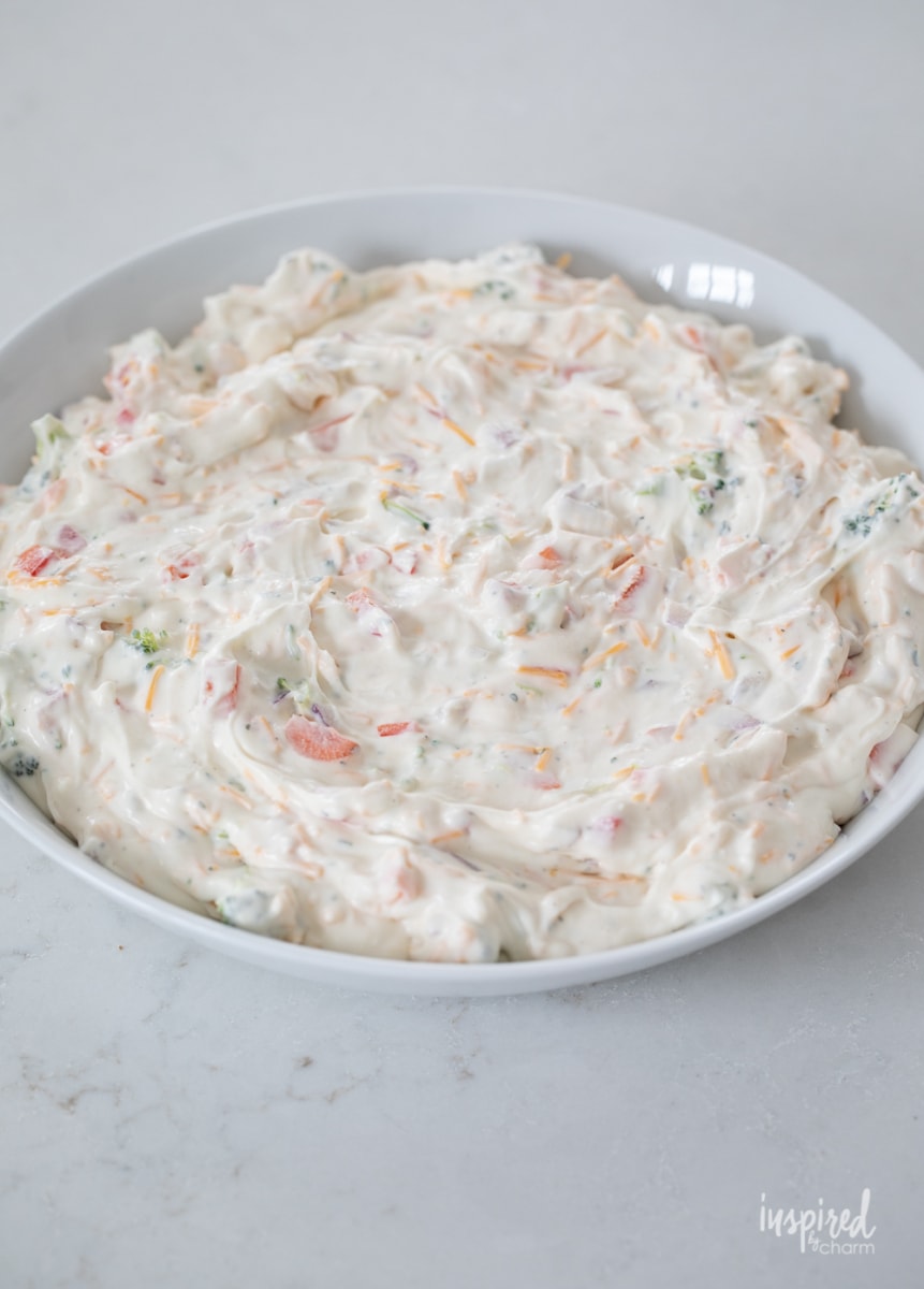 making veggie pizza dip in a bowl