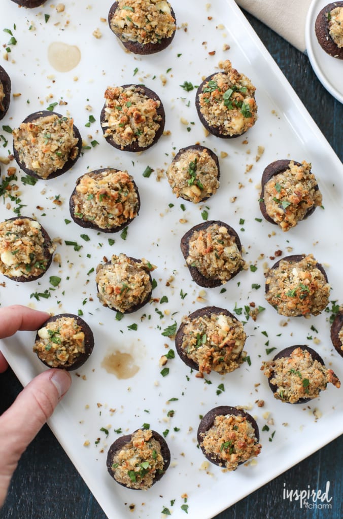 hand taking a Walnut and Blue Cheese-Stuffed Mushroom from a platter.