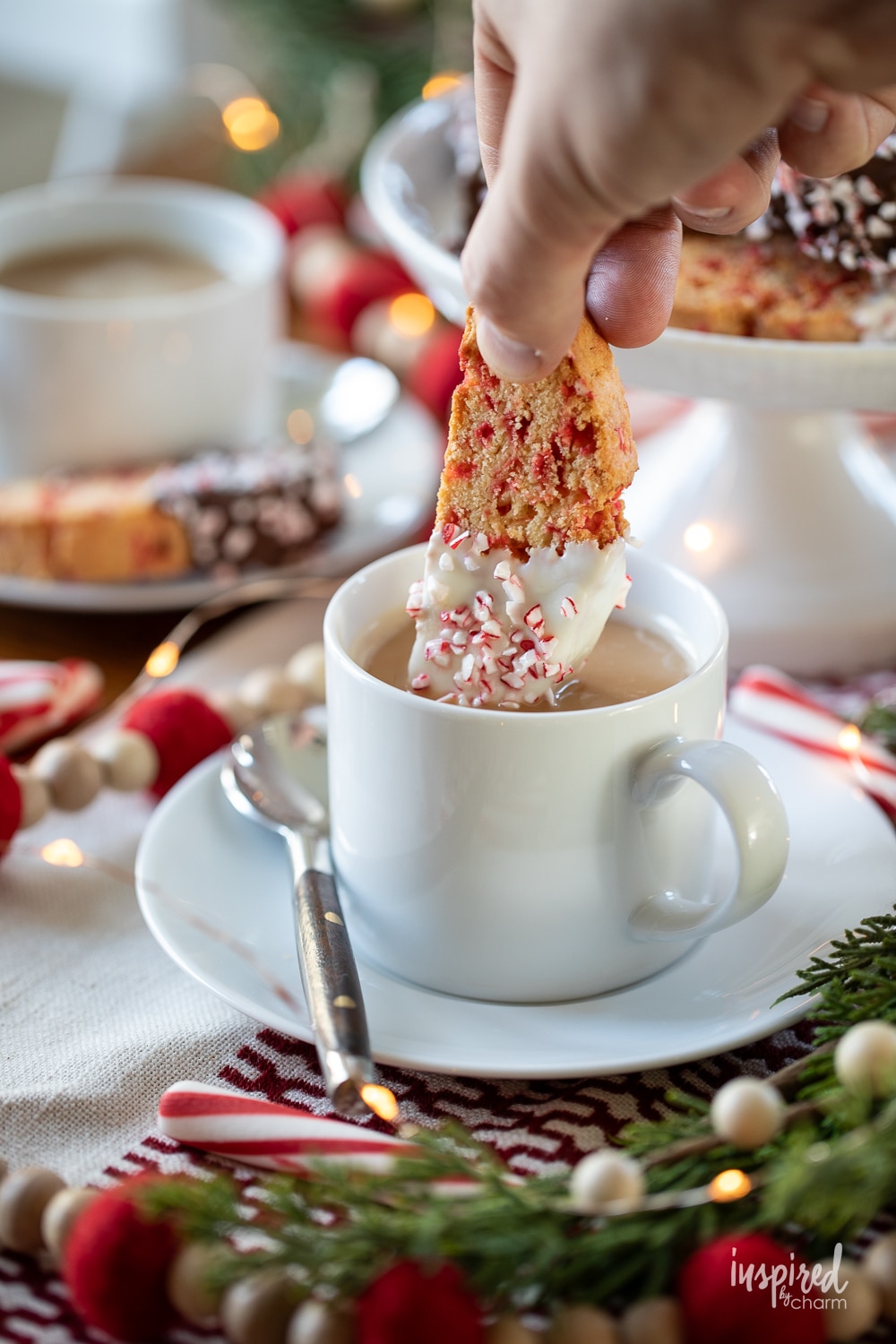 hand dipping peppermint biscotti into a cup of coffee.